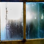 Beschlagene Fensterscheibe mit Kondenswasser am Holzrahmen