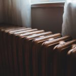 Alter Gussheizkörper unter einem Fenster mit Vorhang im Wohnraum