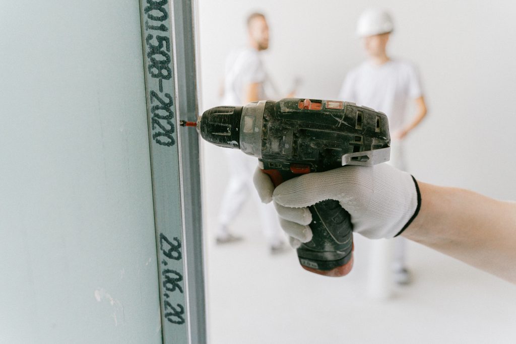 Hand mit Bohrmaschine setzt ein Loch in eine Wand