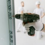 Hand mit Bohrmaschine setzt ein Loch in eine Wand