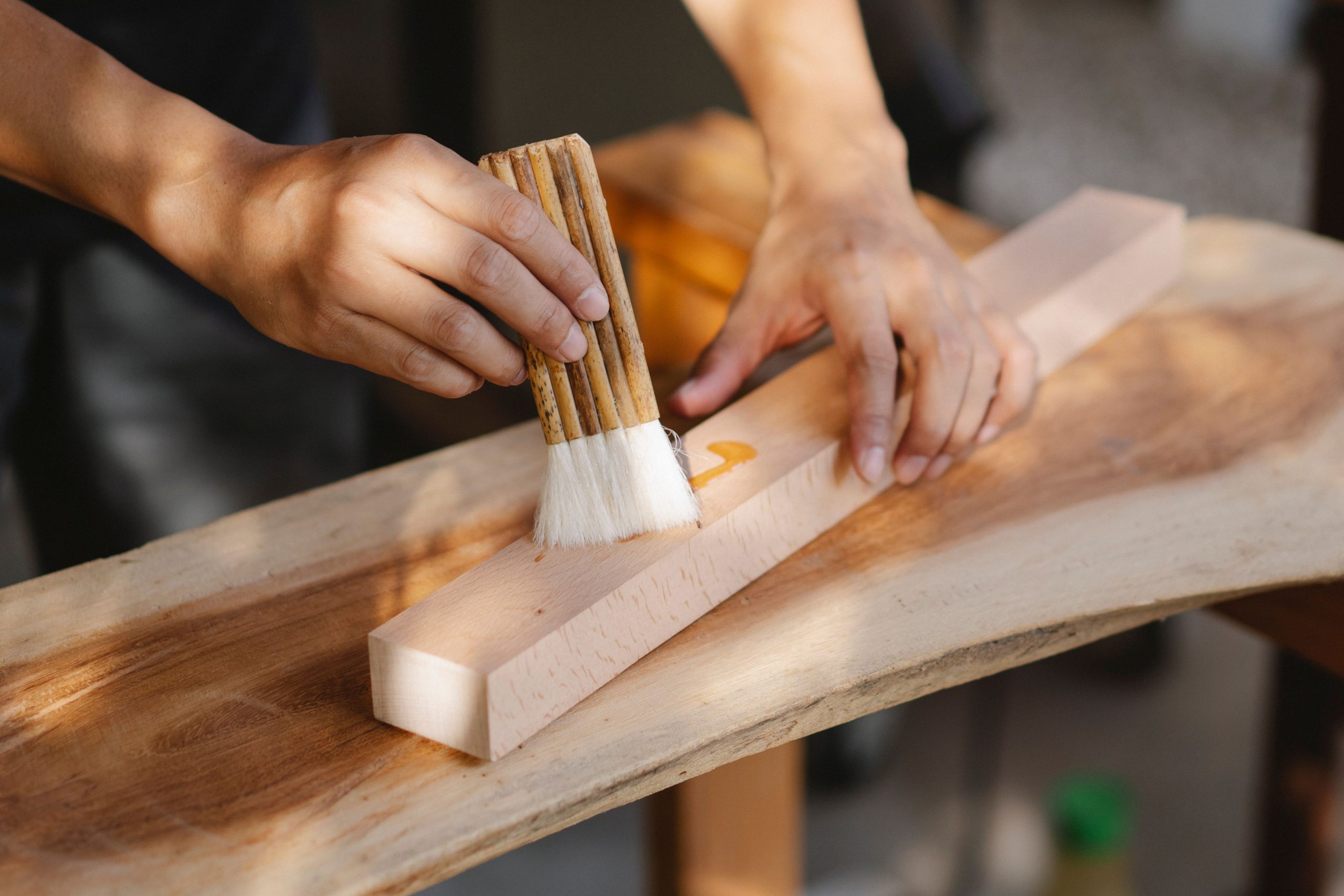 Öl wird mit dem Pinsel dünn auf ein Holzbrett aufgetragen