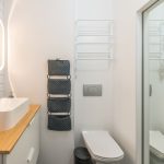 Kleines Badezimmer ohne Fenster mit beleuchtetem Spiegel über dem Waschbecken
