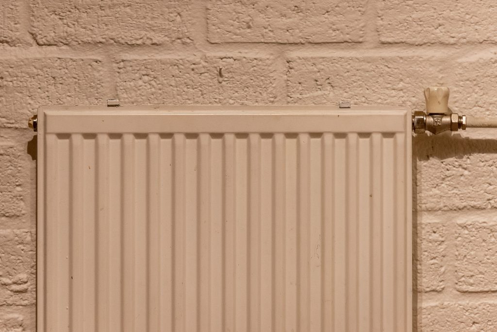 Weißer Heizkörper an einer hellen Backsteinwand