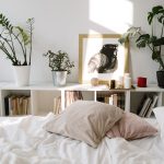Sonniges Schlafzimmer mit weißer Bettwäsche und Zimmerpflanzen